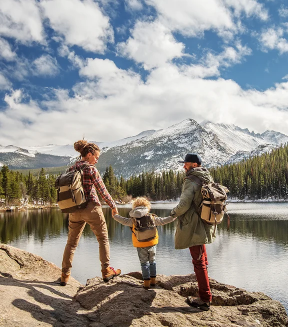 A family stands on a boulder at the edge of a mountain lake